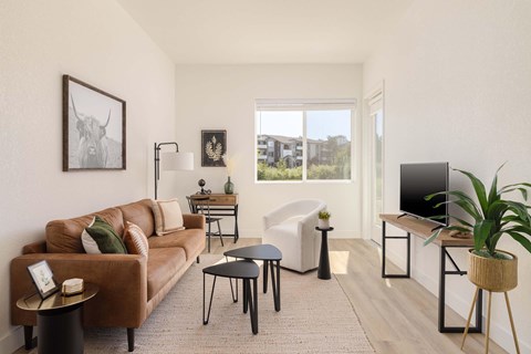 A living room with a brown couch, a white chair, and a TV on a stand.