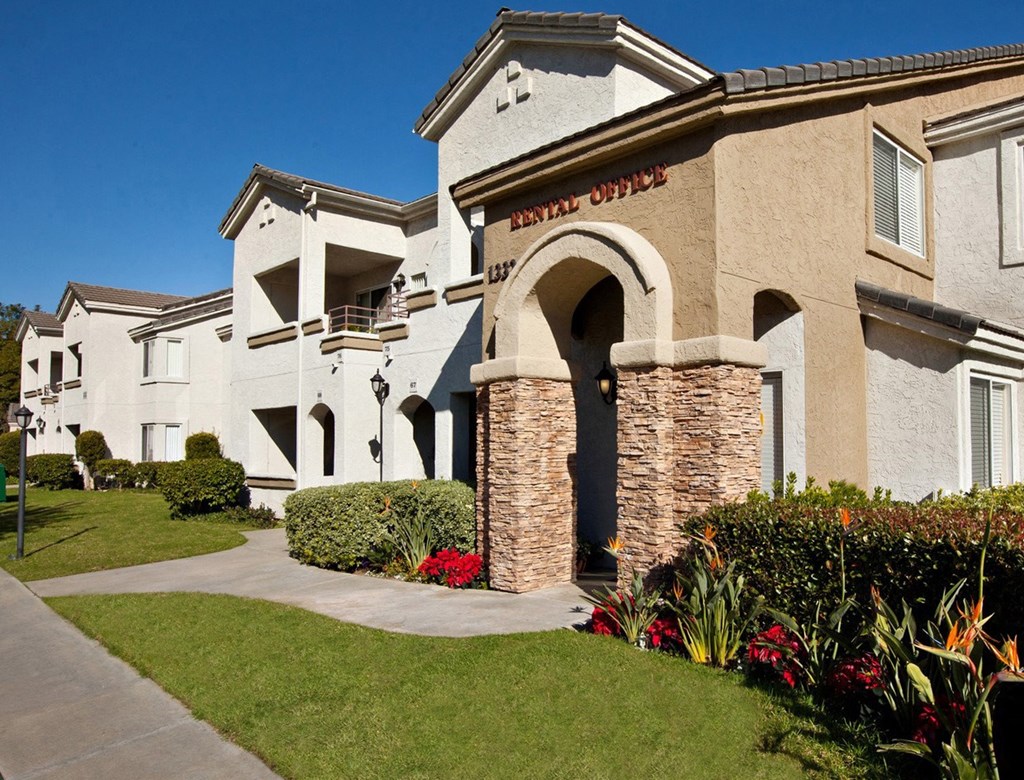 a large white building with a sidewalk in front of it and a blue sky in the background