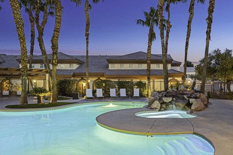 A pool surrounded by palm trees and a house in the background.