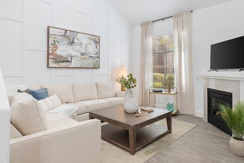 A living room with a white couch and a painting on the wall.