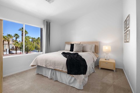 A bedroom with a large bed and a window overlooking a street.