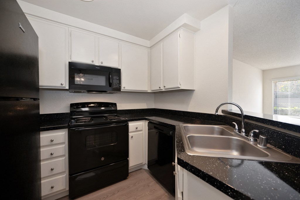 Kitchen area with black counters and appliances