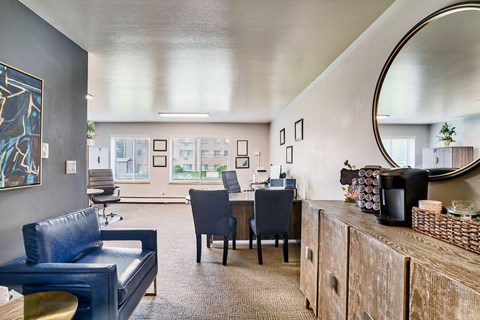 A modern leasing office space with a blue couch, a desk with a computer, and a mirror on the wall.
