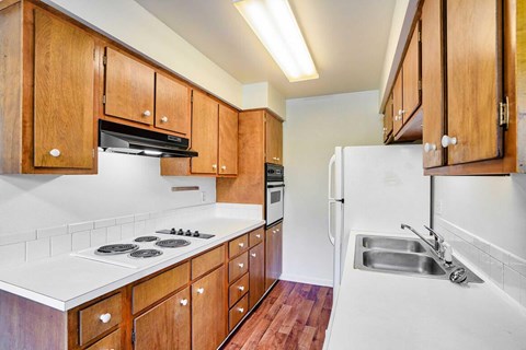 A kitchen with wooden cabinets and a white countertop and fridge.