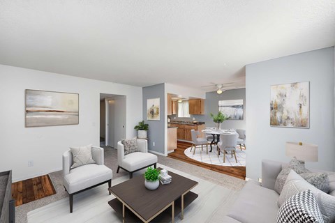 A living room with Wood-Style Vinyl Plank Flooring and a large window, The room is staged with a couch, 2 chairs, and a painting