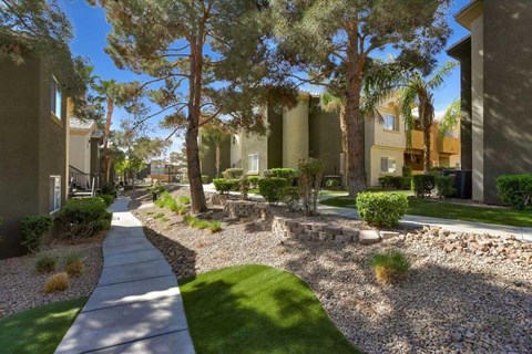 A residential area with a sidewalk and a grassy area.