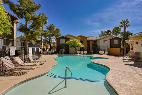A swimming pool surrounded by lounge chairs and trees.