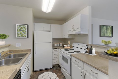Kitchen with white appliances, white cabinets, and overhead light.
