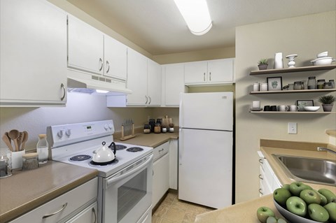 Kitchen with white appliances, white cabinets, and overhead light.