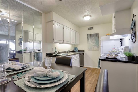 A modern kitchen with a dining table set for two.