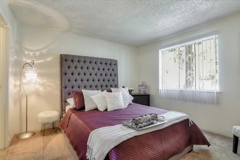A bedroom with a large bed and a window with curtains.