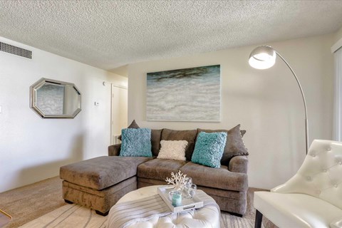 A living room with a brown couch and a white chair.