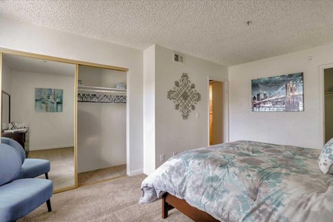 A bedroom with a bed, a couch, and a painting on the wall.