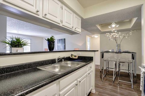A kitchen with a black granite countertop and white cabinets.