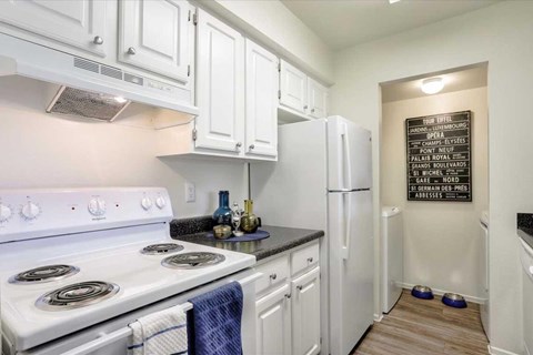 A kitchen with white cabinets and a white stove top oven.