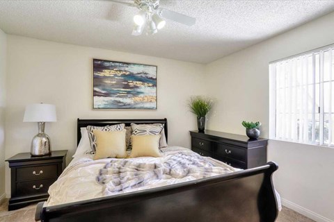A bedroom with a large bed, a nightstand with a lamp, and a painting on the wall.