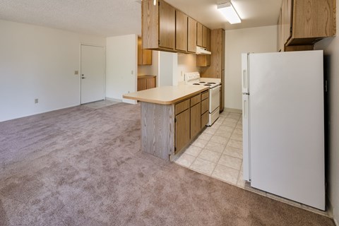 A kitchen with a white refrigerator and wooden cabinets.