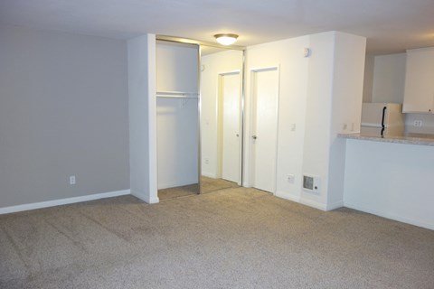 an empty living room with white walls and a kitchen