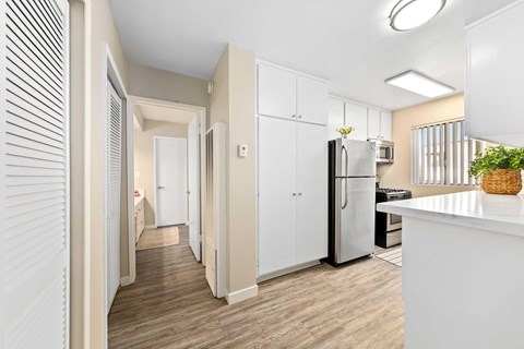 Kitchen with stainless front appliances, beige walls, white cabinets, and quartz countertops.
