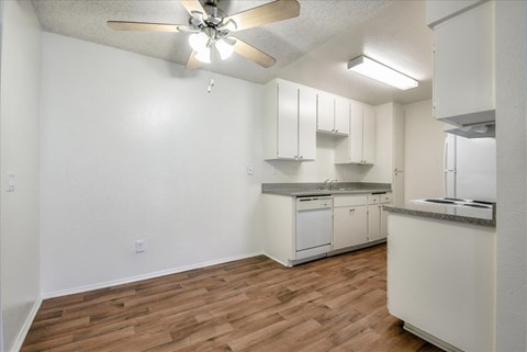 A kitchen with white cabinets and a ceiling fan.