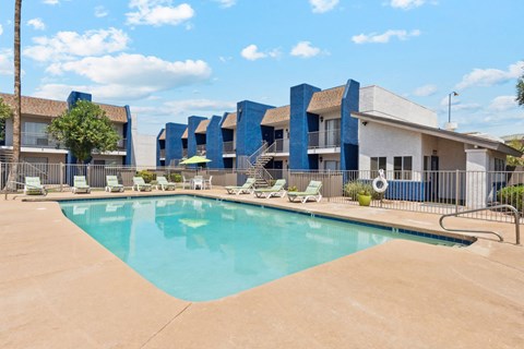 A swimming pool in front of a building with blue and white walls.