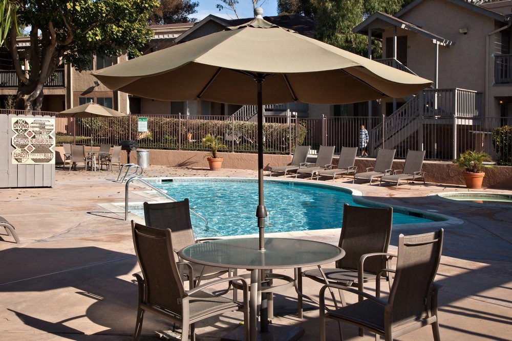 a swimming pool with a table and chairs under an umbrella