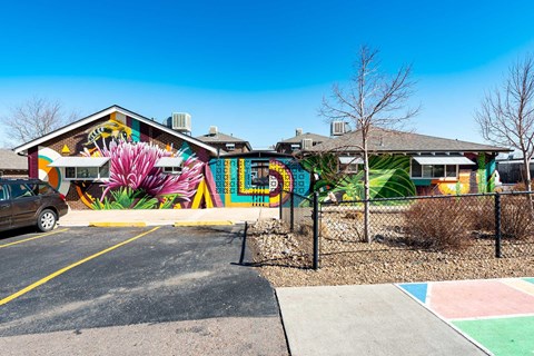 A mural of a pink flower is on the side of an apartment building.