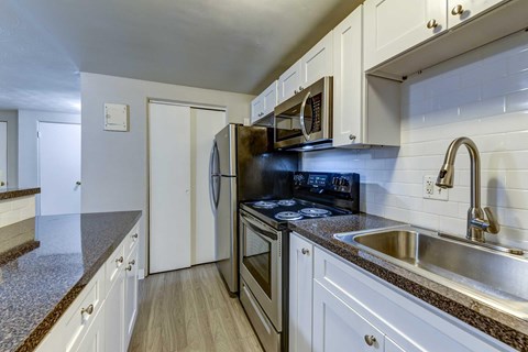A kitchen with a black stove top oven and white cabinets.
