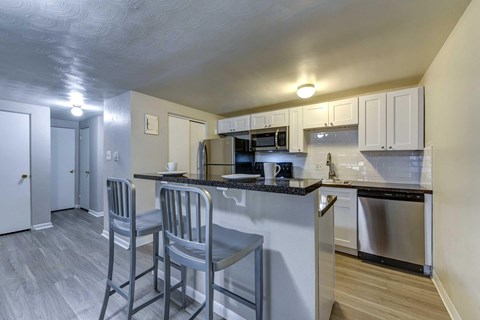A kitchen with two bar stools and a counter.