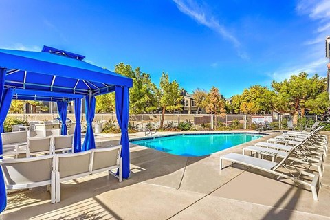 A pool area with sun loungers and a blue canopy.