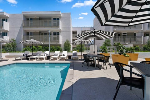 The community's pool area with chairs and umbrellas on a sunny day.