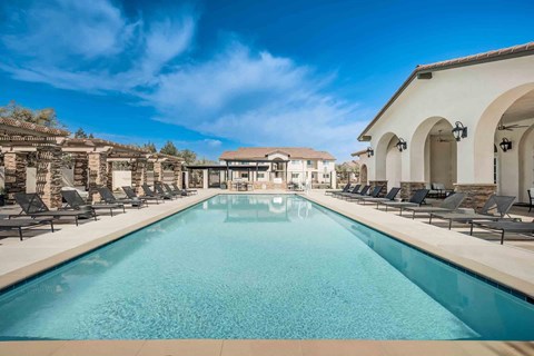 A large lap swimming pool surrounded by lounge chairs.