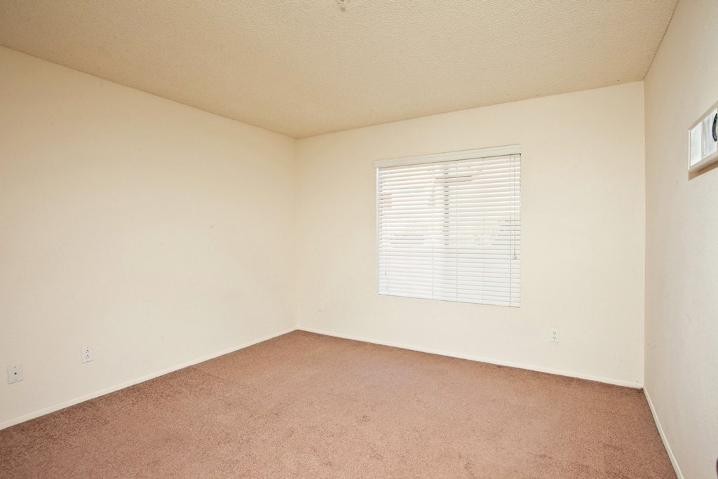 a bedroom with white walls and a window