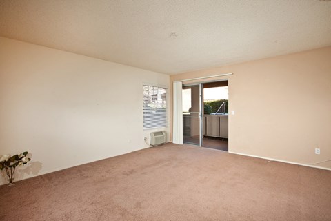 a living room with carpet, white walls, and a sliding glass door to get onto the balcony.