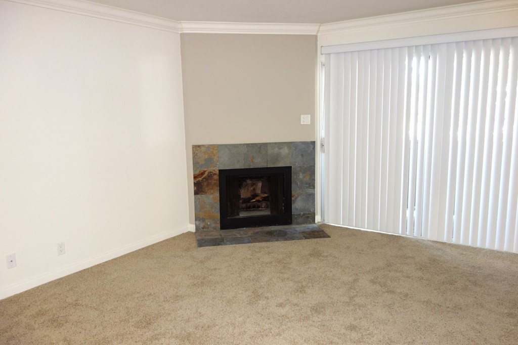 a living room with a fireplace and a window with white blinds