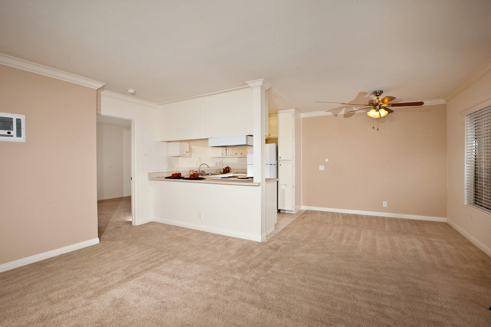 an empty living room and kitchen with a ceiling fan