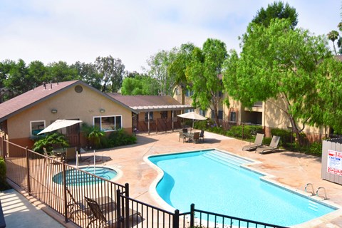 The community swimming pool with spa and lawn chairs surrounding the pool.