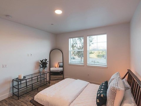 A bedroom with a large bed, a window with a view, and a nightstand with a plant on it.