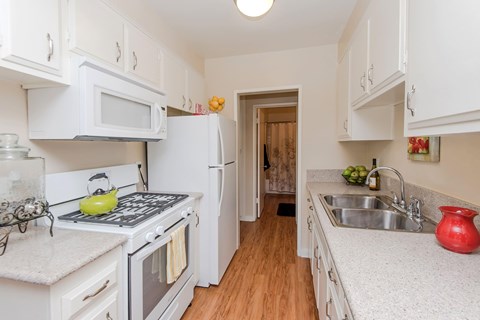 The kitchen with white appliances, hard wood style floors, granite countertops, and white cabinets.