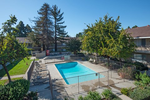 The gated pool area with trees and grass surrounding outside of the gates.