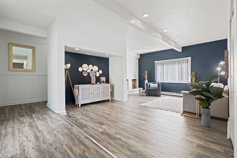 A community room with a grey sofa and a white cabinet stand with mirrors over it.