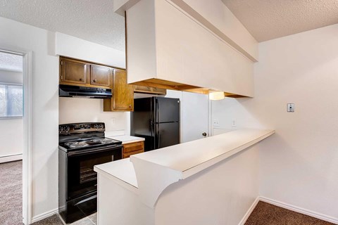 A kitchen with a black stove top oven, breakfast bar, and a black refrigerator.