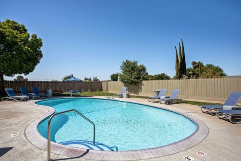 The pool at Village Ceres with lounge chairs and umbrellas surrounding.