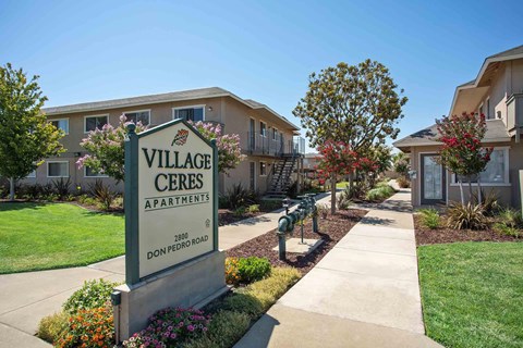 A sign for Village Ceres Apartments stands in front of the community building.