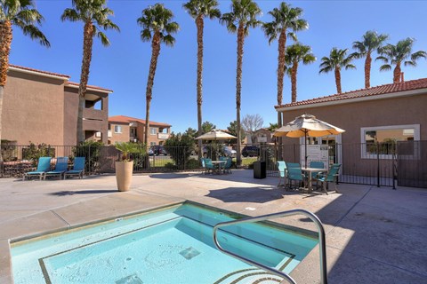 A hot tub surrounded by palm trees and chairs.