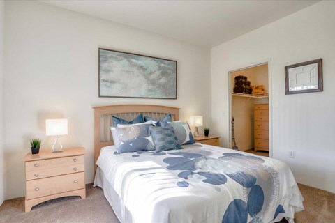 A bedroom with a bed, nightstand, and a painting on the wall.