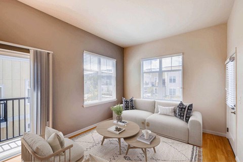 A living room with a white couch, a coffee table, and windows.