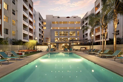 A large rectangular pool in the center of the courtyard with lounge chairs.