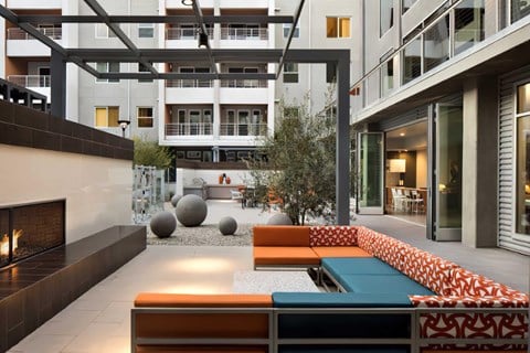 A modern outdoor seating area with a fireplace and a variety of seating options.