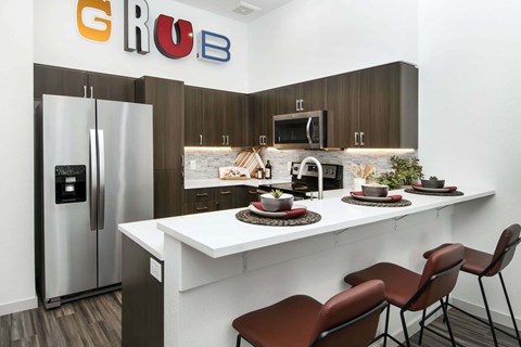 A kitchen with a white counter and brown chairs.